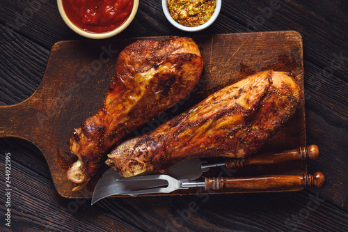 Roasted turkey legs, on dark wooden background.