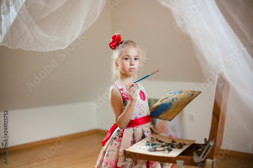 little girl lying on the floor and drawing with colored pencils photo