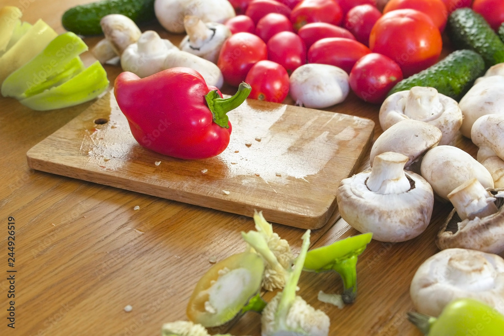 Red pepper on wooden board on kitchen table with vegetables and mushrooms. Red pepper on wooden board on kitchen table with vegetables and mushrooms.