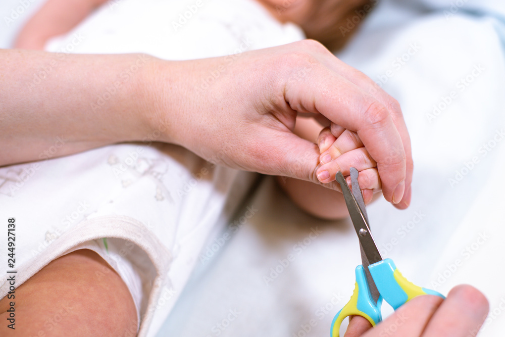 Close up of mother cutting babies nails with scissors. Nursing a child.