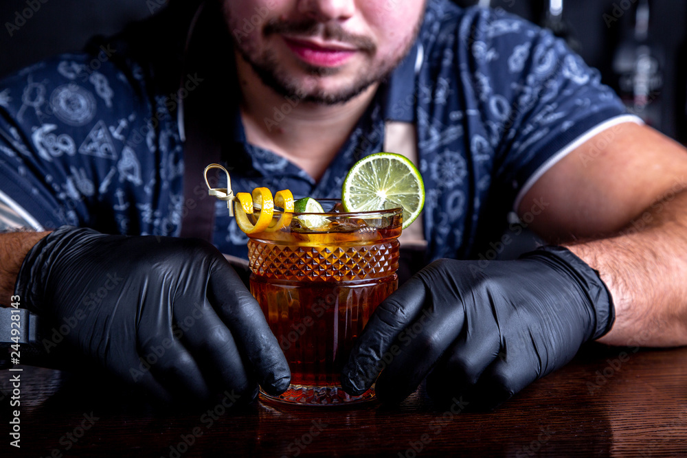 Barman holds out cocktails to client at the bar in restaurant. Welcome Barman holds out cocktails to client at the bar in restaurant. Welcome