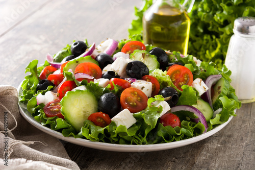 Fresh Greek salad in bowl with black olive,tomato,feta cheese, cucumber and onion on wooden table.