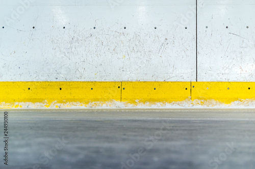 Hockey rink boards with scratched and damaged surface and ice floor
