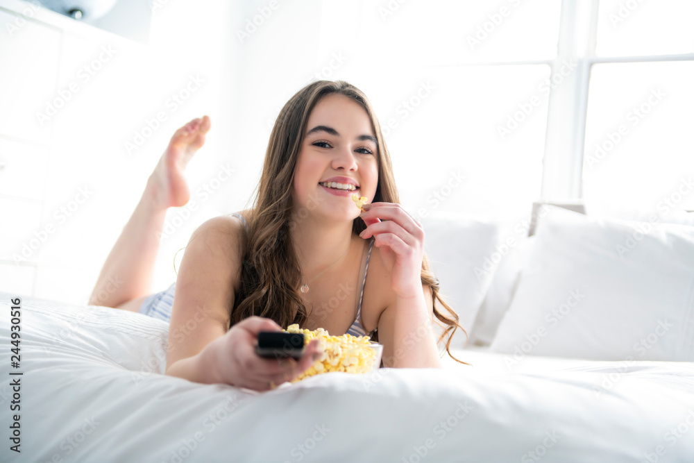 A young teenager watching movies in bed with popcorn A young teenager watching movies in bed with popcorn