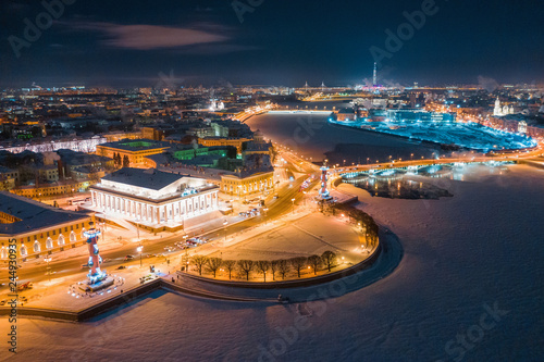 Aerial view of Rostral Columns in Vasilievskiy Island, night lights, river Neva frome drone