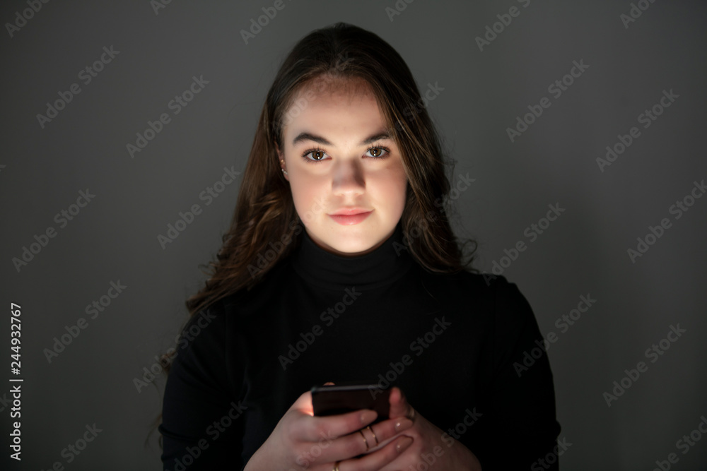 A young teenager girl using mobile phone in dark room A young teenager girl using mobile phone in dark room