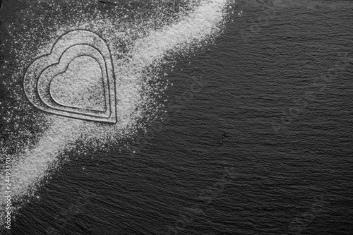 three powder hearts in sugar or flour optic on a black slate stone surface
