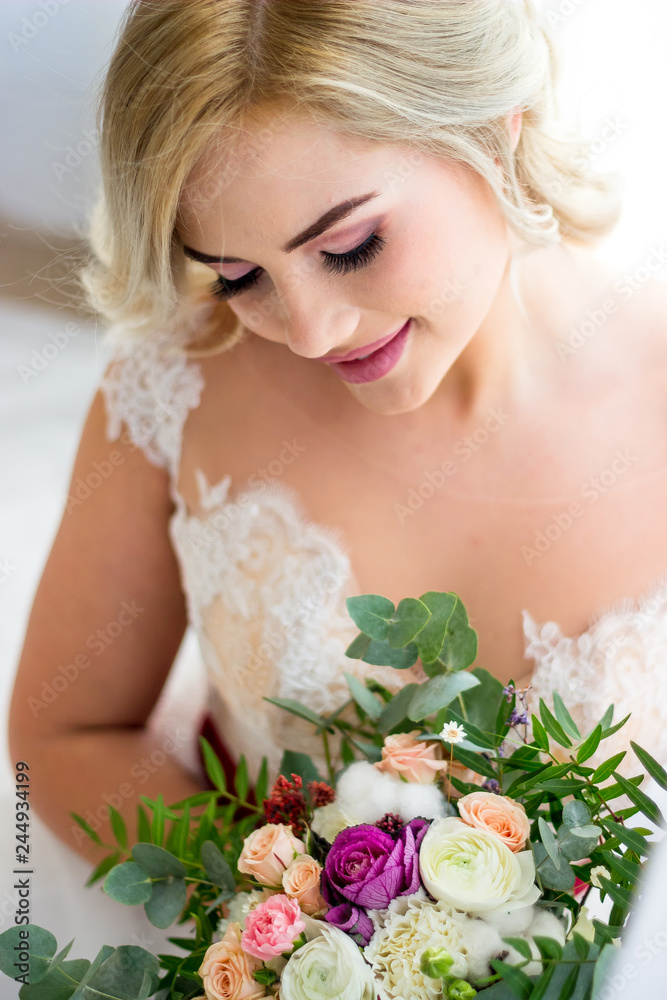 Naklejka premium The morning of a beautiful bride dressed in a peignoir surrounded by flowers.