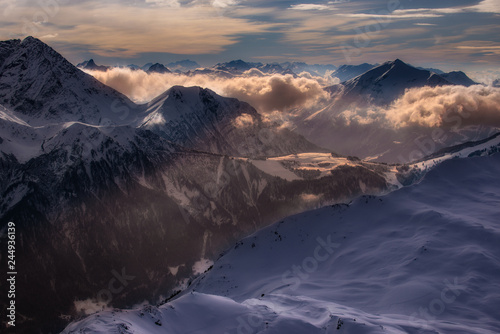 Fantastic dreamy sunrise on top of rocky mountain with view into misty valley. Foggy mountain. Sunset clouds. Misty peaks. Foggy landscape. Top of High mountains, covered by snow.