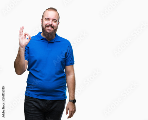 Young caucasian hipster man wearing blue shirt over isolated background smiling positive doing ok sign with hand and fingers. Successful expression.