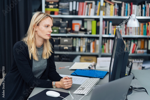 Young woman sitting working at a desktop computer photo