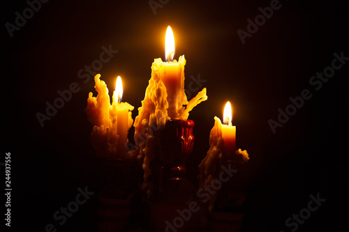 background of burning candles in a candlestick, the wax melts from the fire and flows down in the dark