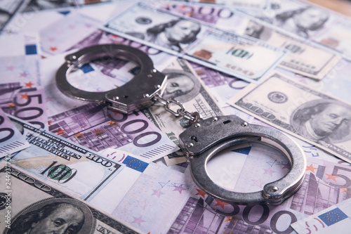Metallic handcuffs with money. Financial crime concept