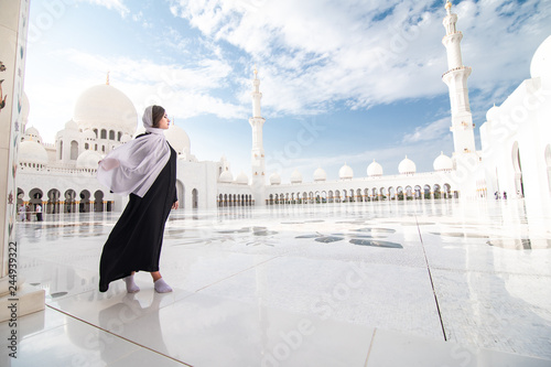 Traditionally dressed arabic woman wearing black burka visiting Sheikh Zayed Grand Mosque in Abu Dhabi, United Arab Emirates.