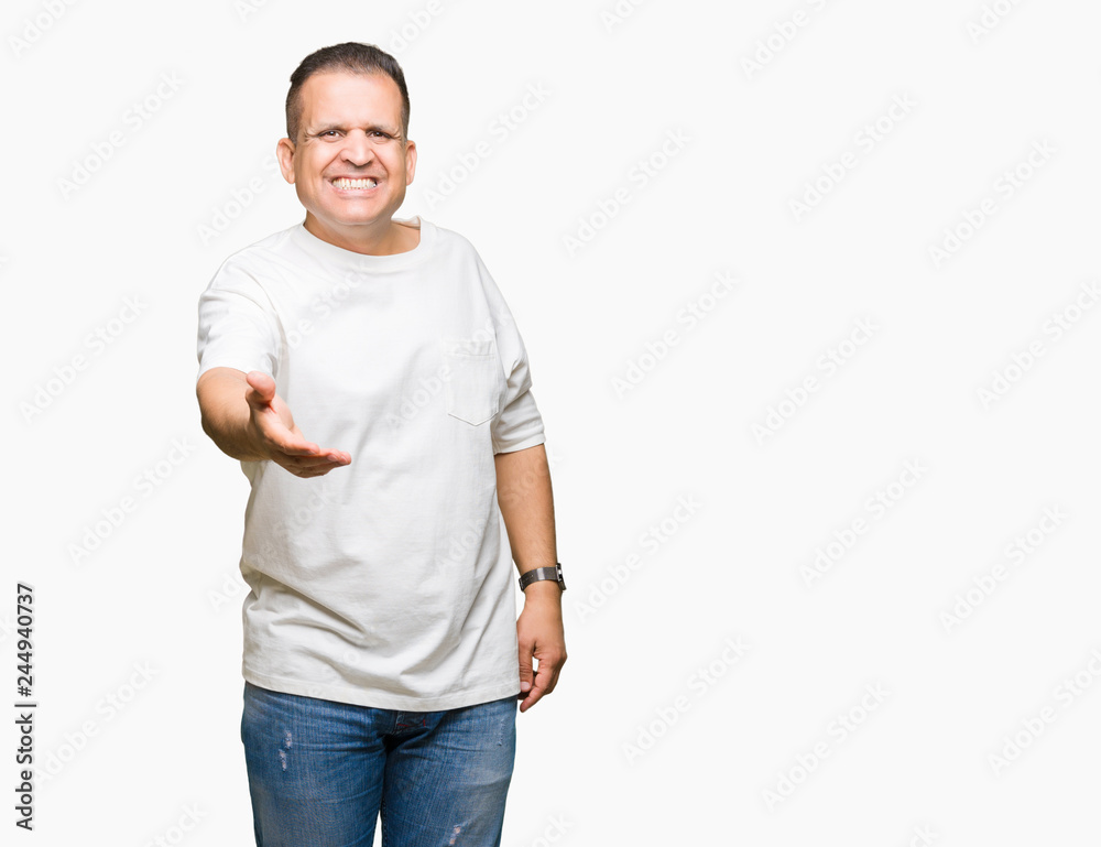 Middle age arab man wearig white t-shirt over isolated background smiling friendly offering handshake as greeting and welcoming. Successful business. Middle age arab man wearig white t-shirt over isolated background smiling friendly offering handshake as greeting and welcoming. Successful business.
