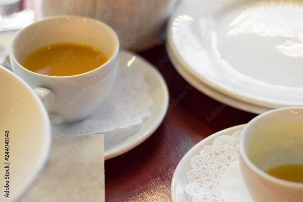 white cups of yellow sandhorn tea on wooden table sufounded by dishes, Selective focus