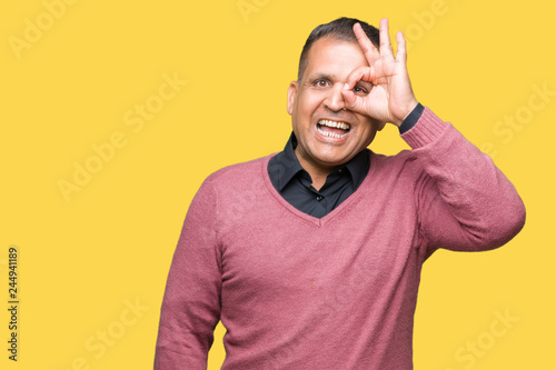 Middle age arab man over isolated background doing ok gesture with hand smiling, eye looking through fingers with happy face. © Krakenimages.com