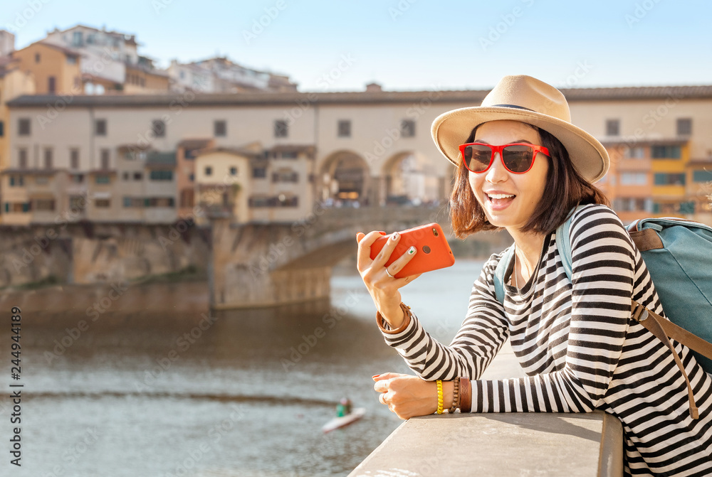 Happy asian young traveler girl taking selfie near Ponte Vecchio Bridge
