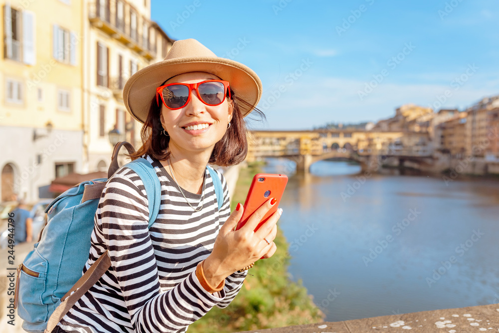 Fototapeta premium Happy traveler asian women on a vacation in Florence admiring view at the Ponte Vecchio famous landmark during trip in Italy, Europe