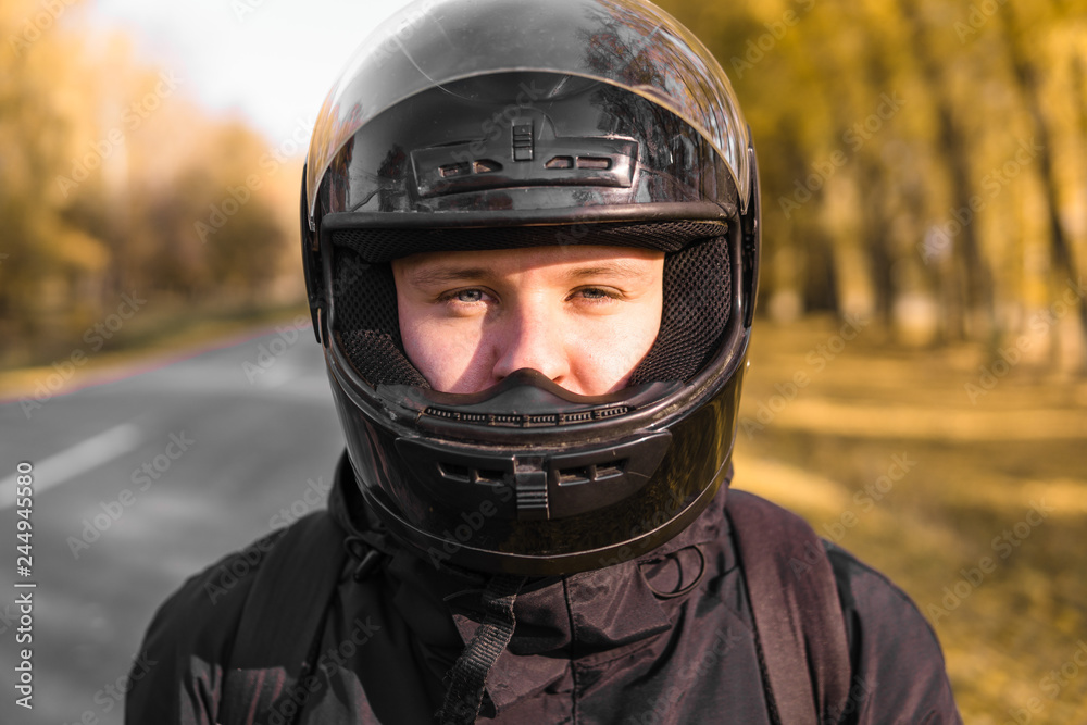portrait of a biker, rider standing on the road. dressed in black portrait of a biker, rider standing on the road. dressed in black