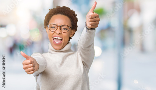 Young beautiful african american woman wearing glasses over isolated background approving doing positive gesture with hand, thumbs up smiling and happy for success. Looking at the camera