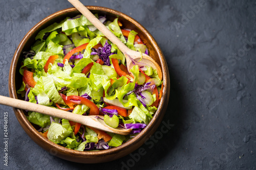 Mix salad leaves in a black bowl over dark slate, stone or concrete background.