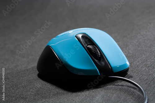 Small computer mouse plastic. Blue color. Black background. Black wire. A blank space for an inscription. Electronics.