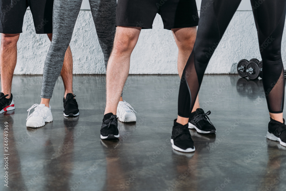 low section of young people in sportswear and sneakers training together in gym low section of young people in sportswear and sneakers training together in gym