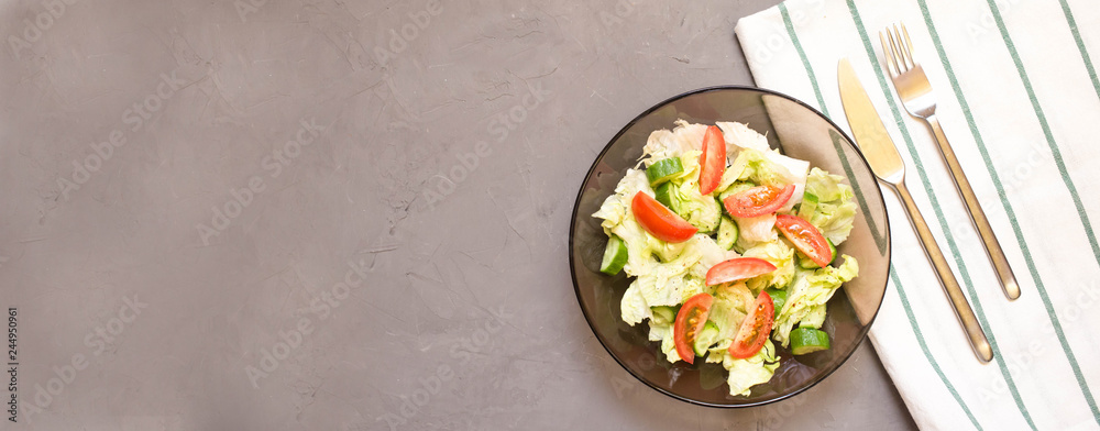 healthy salad, vegetable, tomatoes, cucumbers, iceberg, Cutlery, kitchen towel, grey background. Copy space. Vegetarian healthy salad, vegetable, tomatoes, cucumbers, iceberg, Cutlery, kitchen towel, grey background. Copy space. Vegetarian