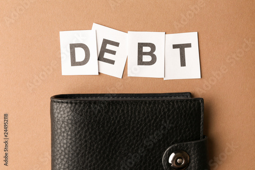 Wallet and word DEBT on color background