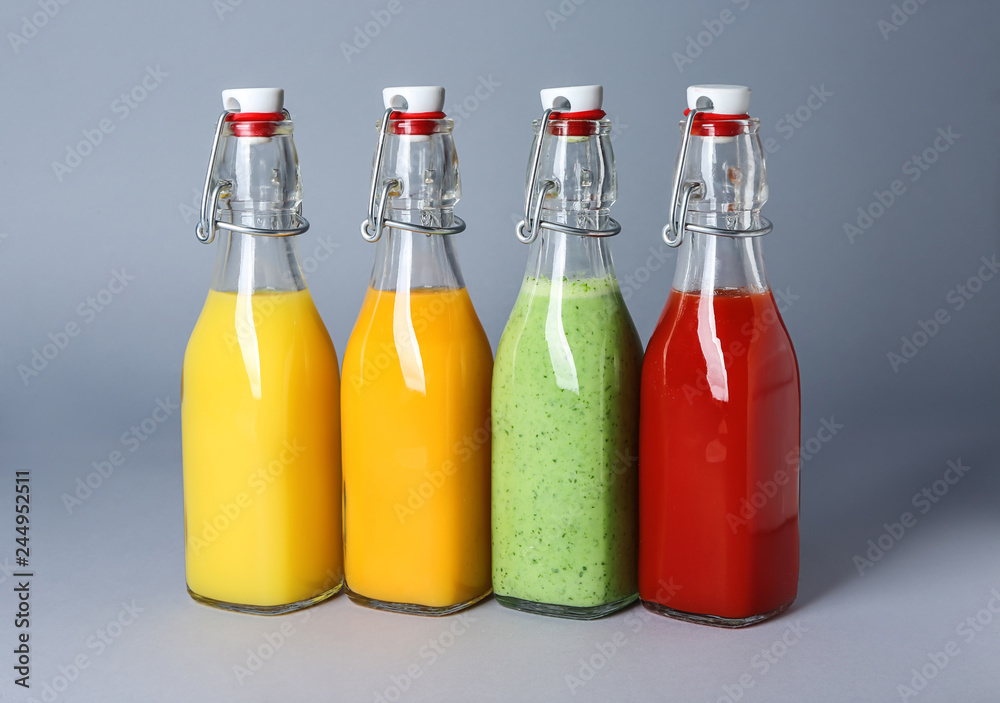 Bottles of healthy juices on grey background Bottles of healthy juices on grey background