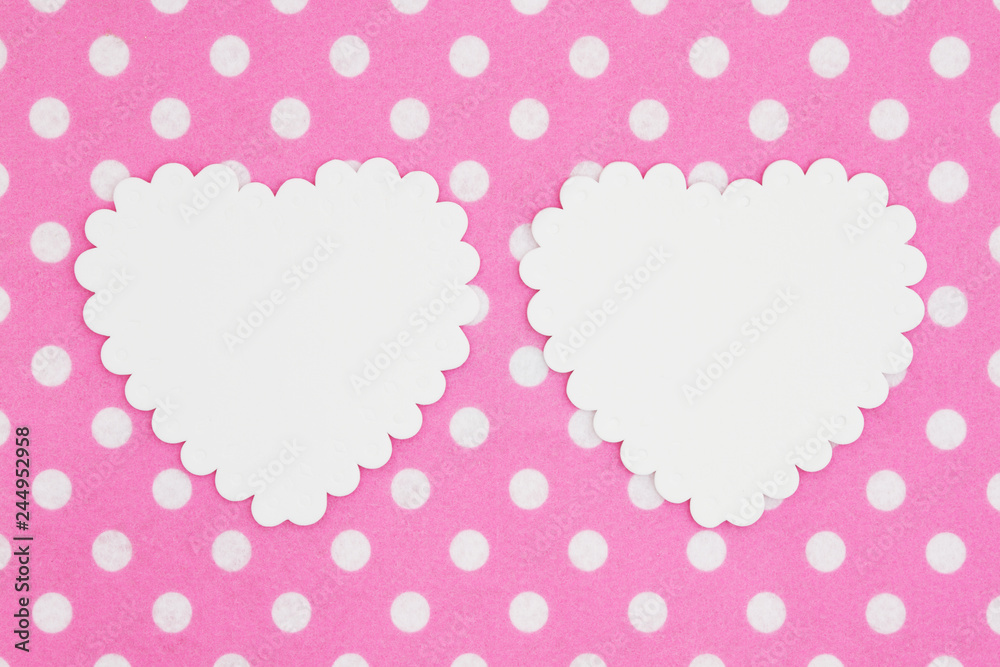 Two blank white hearts on bright pink and white polka dot fabric background
