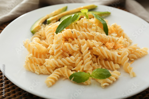 Plate with tasty pasta and avocado on table, closeup