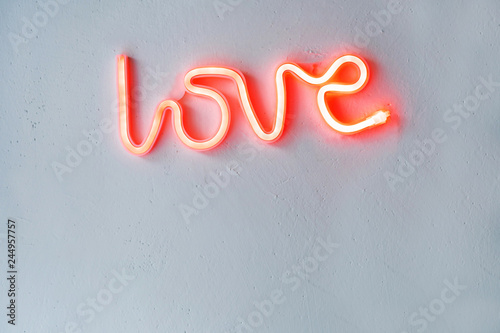 Red Neon Love Sign on a white wall. Selective focus.