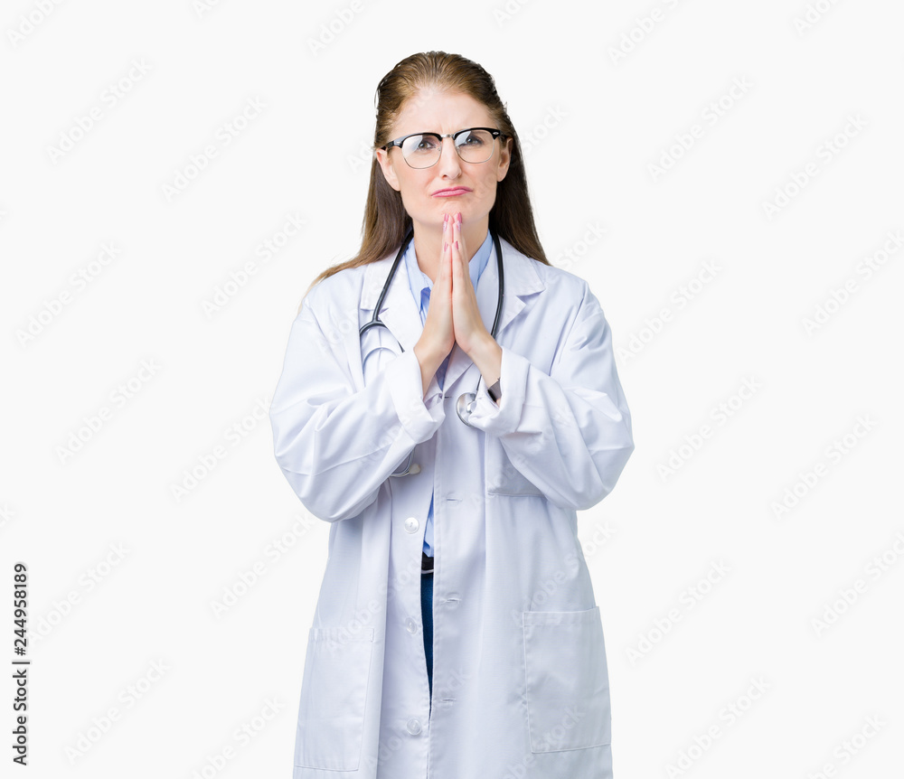 Middle age mature doctor woman wearing medical coat over isolated background praying with hands together asking for forgiveness smiling confident. Middle age mature doctor woman wearing medical coat over isolated background praying with hands together asking for forgiveness smiling confident.