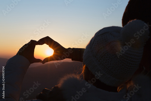 Closeup of couple making heart shape with hands and sunrise background, Couple in love, Focus on hands, Man and woman tourists in the mountains at sunset,  Happy couple in love,  Love couple.