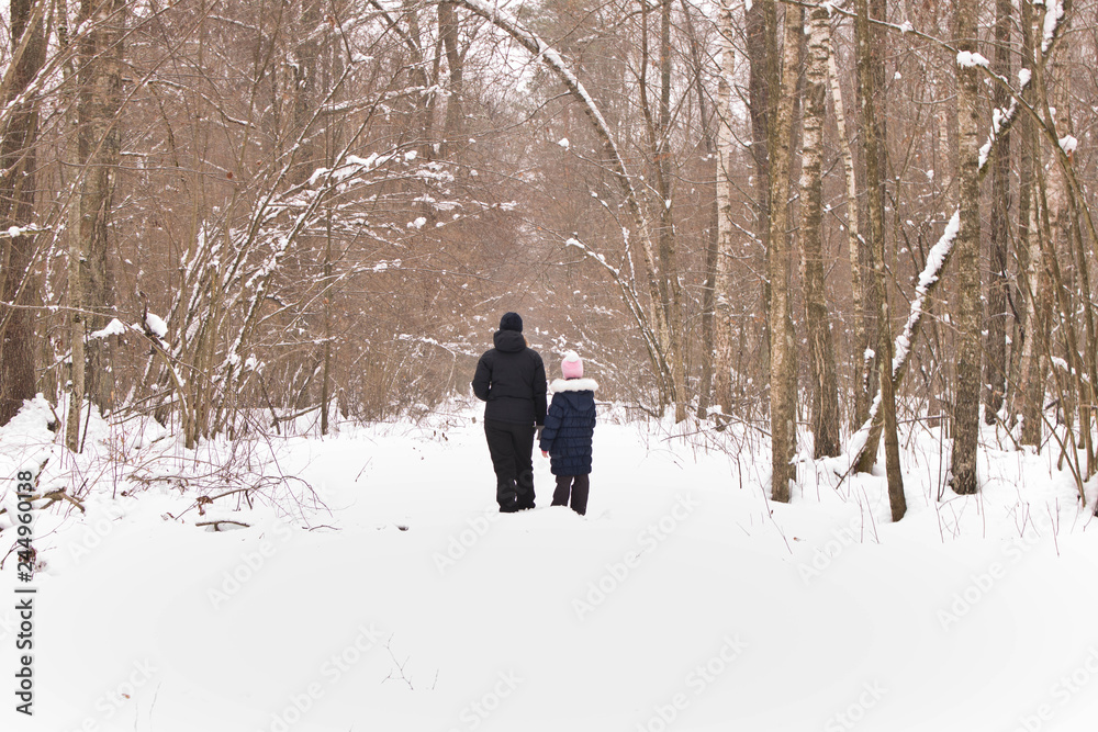 A little girl with her mother in the winter forest. The concept of family.