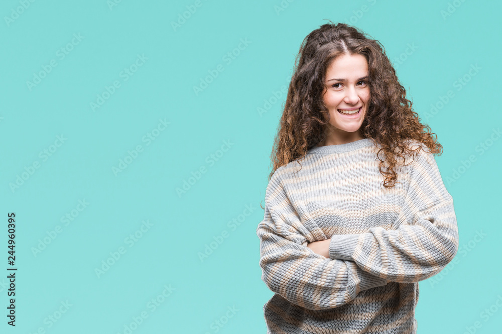 Obraz premium Beautiful brunette curly hair young girl wearing winter sweater over isolated background happy face smiling with crossed arms looking at the camera. Positive person.