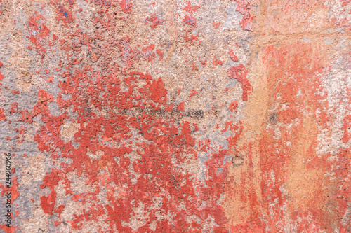 Old weathered painted wall background texture. Red dirty peeled plaster wall with falling off flakes of paint.