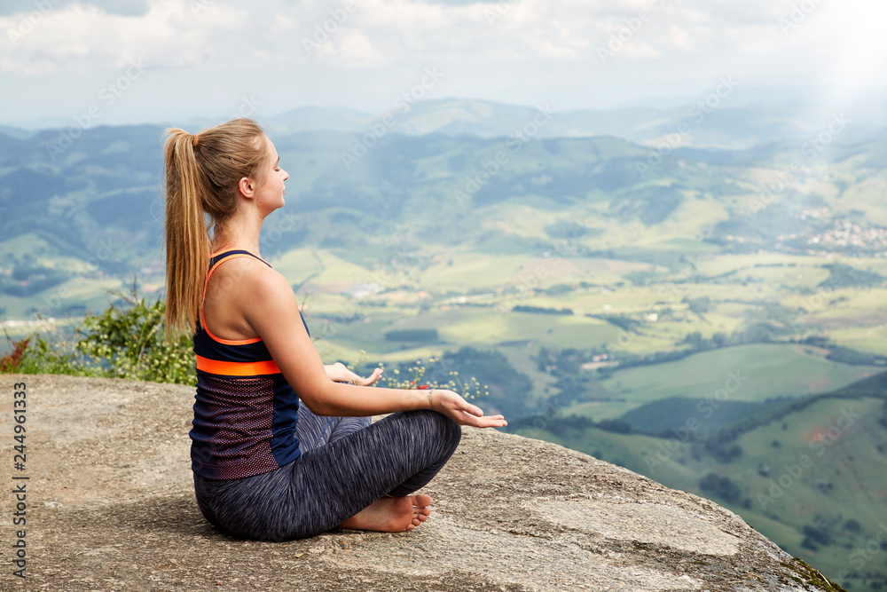 Beautiful woman meditating over landscape