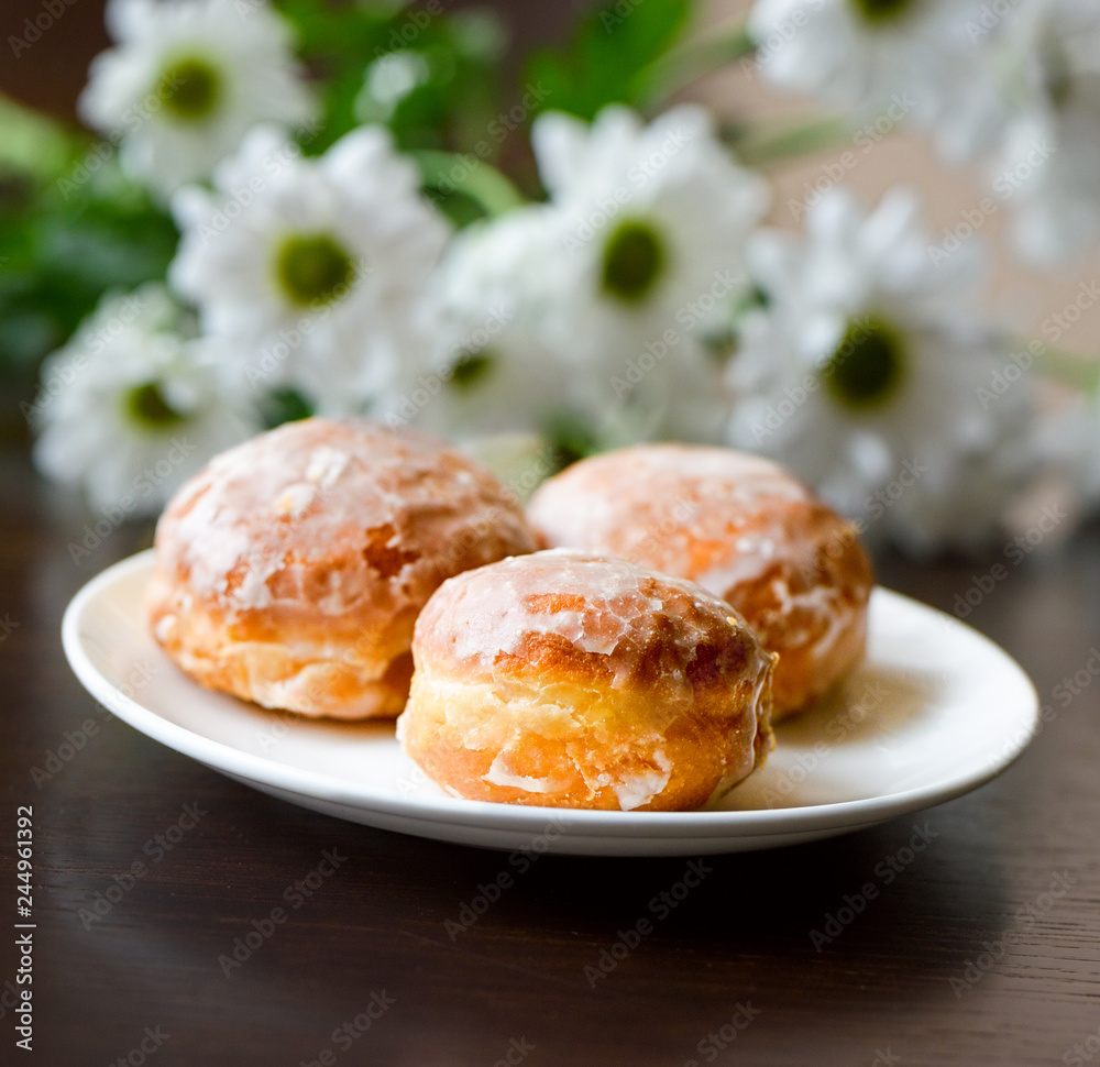 Donuts on a white plate with flower on the table