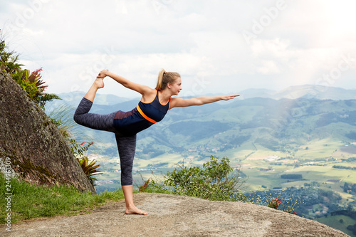 Young woman in yoga pose near cliff edge
