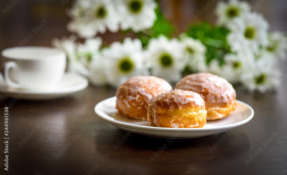 Donuts on a white plate with flower on the table Donuts on a white plate with flower on the table
