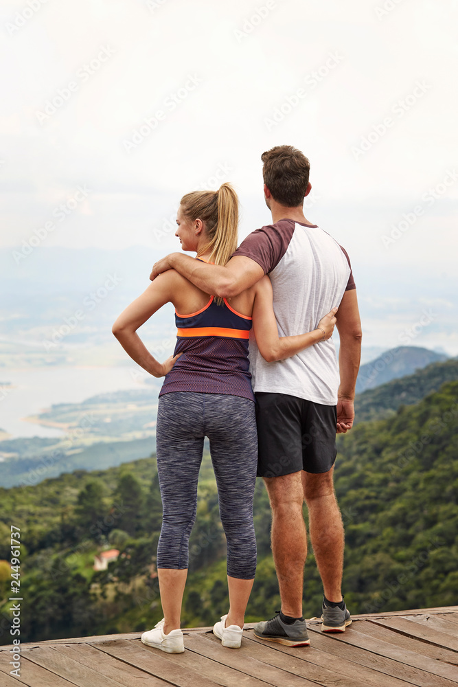 Sporty couple with arms around each other admiring view Sporty couple with arms around each other admiring view
