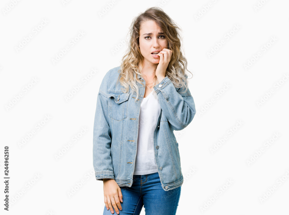 Beautiful young blonde woman wearing denim jacket over isolated background looking stressed and nervous with hands on mouth biting nails. Anxiety problem. Beautiful young blonde woman wearing denim jacket over isolated background looking stressed and nervous with hands on mouth biting nails. Anxiety problem.