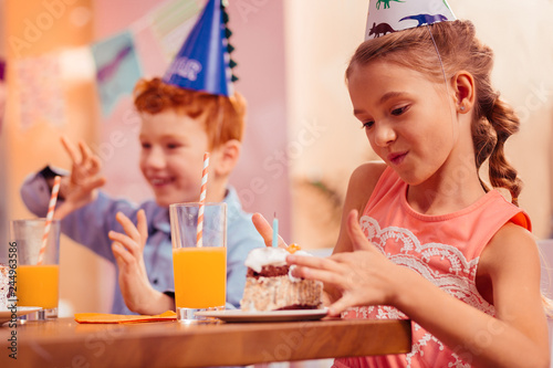 Kind blonde girl looking at piece of cake