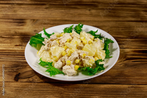 Festive salad with chicken breast, sweet corn, canned pineapple and mayonnaise on wooden table