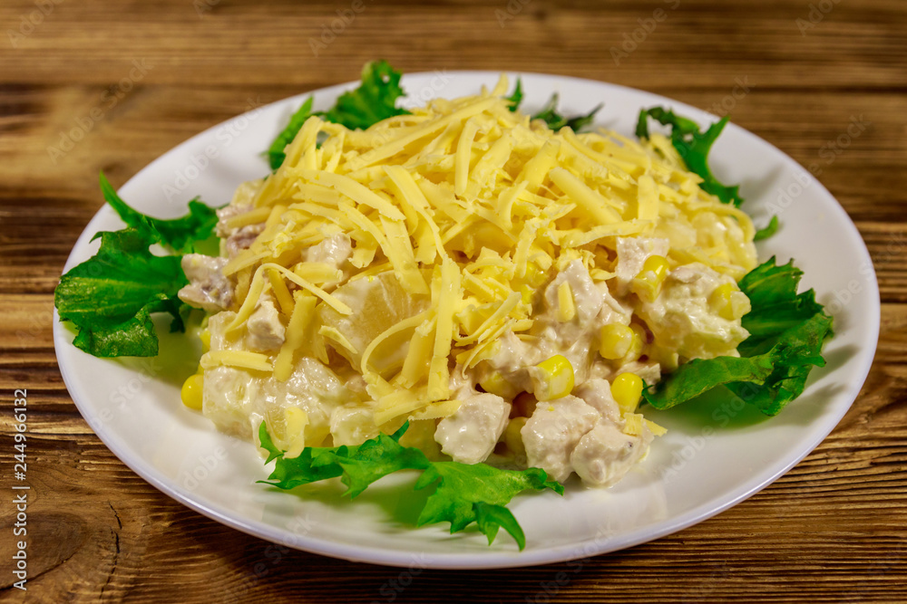 Festive salad with chicken breast, sweet corn, canned pineapple, cheese and mayonnaise on wooden table Festive salad with chicken breast, sweet corn, canned pineapple, cheese and mayonnaise on wooden table
