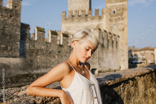 young beautiful girl in a white dress is standing at dawn on the background of the castle