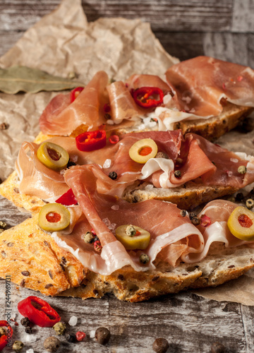 Bruschetta with roasted bell pepper, prosciutto, garlic, olives, spices and herbs. Appetizers.